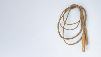 A old skipping rope hanging on a white wall. - obrazy, fototapety, plakaty