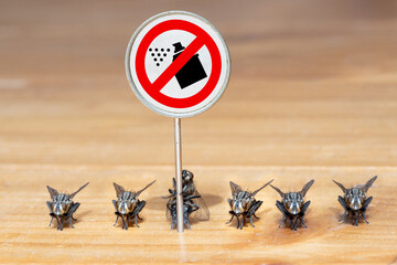 The flies stands in line with an board with a symbol ban of insecticides.