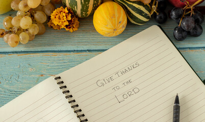Give thanks to the LORD, a handwritten quote in an open notebook with pen and fall fruits:...