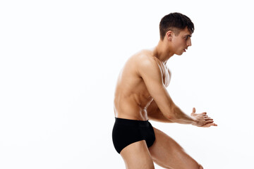 Obraz premium side view of a sexy athlete with a pumped-up torso and in black shorts on a white background