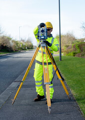 Site engineer installing robotic total station on top of wooden tripod to perform surveying and setting out