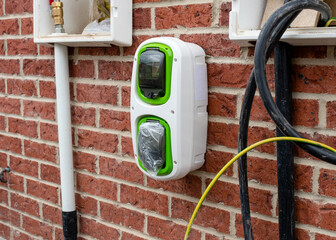 Domestic electric vehicle charging point fitted on the wall of new build house as part of the...