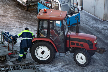 A ground staff of the airport manipulate with trolley for connect at tractor.