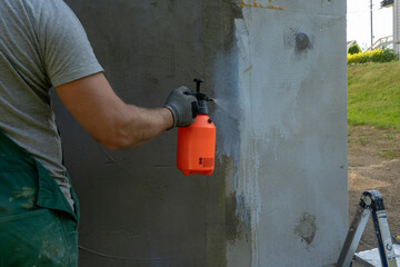 Spraying reinforcing liquid on cement mortar on the wall.