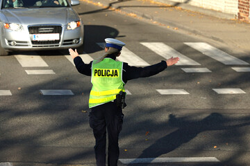 Policjant drogówki kieruje ruchem drogowym w mieście. 
