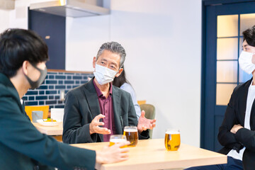 マスクをしてレストランで会話をする人々