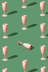 Pattern made of pink champagne glasses on a green background. New year Christmas party celebration concept