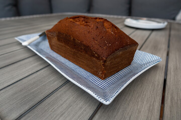 Wide angle view of home baked banana bread served on a blue and white rectangle dish with plates...