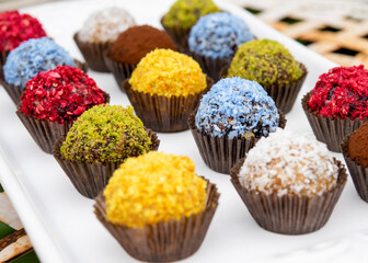 a few colourful sweet balls on a white table outside	
