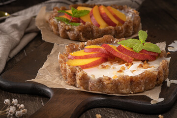 Nectarine vegan tarts with grated coconut and crunchy peanuts. Date, walnut, almond and hazelnut base.