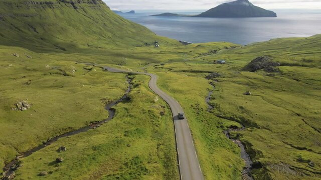 Drone Of Car Driving Along Winding Road In Dramatic Countryside Of Faroe Island