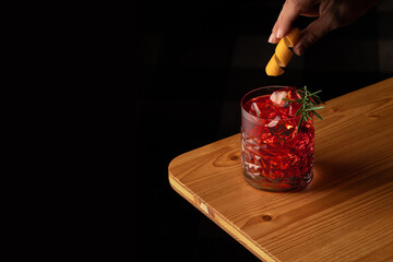 negroni cocktail su tavolo di legno, con scorza di arancia su sfondo scuro	