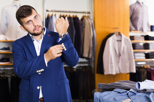 Young male customer choosing jacket in men fashion store