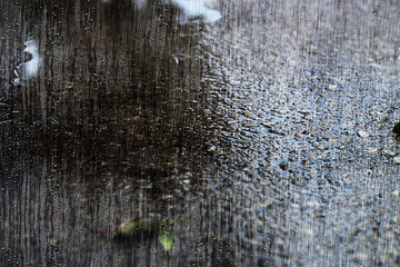 Rain in Israel has created a puddle on the street, there is a flood threat and danger flooding. Photo Effect of raindrops on glass