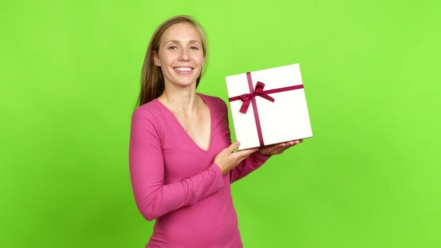 Young blonde girl happy and holding a gift over isolated background. Green screen chroma key