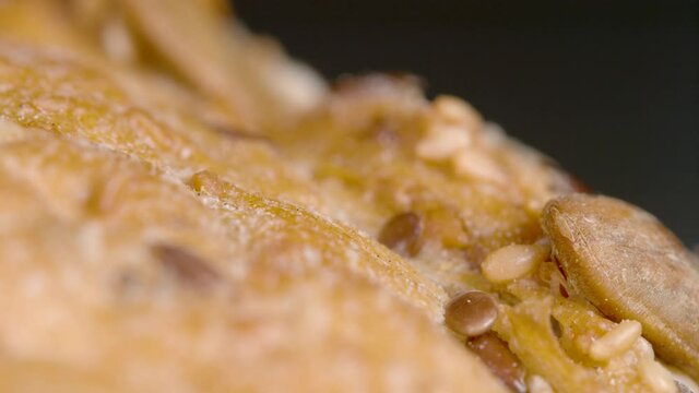 MACRO, DOF: Freshly baked homemade rustic loaf of bread sits on the kitchen table. Detailed close up shot of the crispy crust of a homemade high-protein unleavened bread sitting on the countertop.