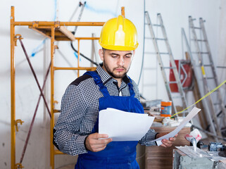 Diligent serious builder is looking on the project of work for the object.