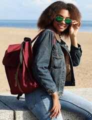 Young african american girl in sunglasses, posing outdoors, Dressed casual, with short voluminous hair.