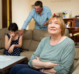Senior woman sitting during family conflict, woman crying while quarrel with man