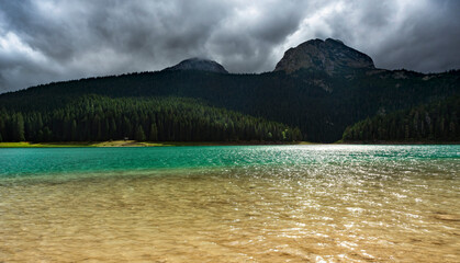 Colors of Black Lake,sun shining into lens and Mount Durmitor,Montengro,Eastern Europe.