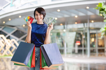 Young beautiful happy woman holding colorful shopping bags and showing her credit cards