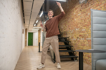 A young man looking happy and enjoyed in the office corridor