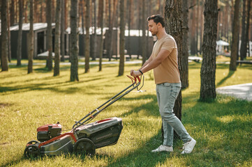 Profile of man with grass-cutter on lawn