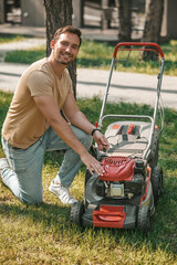 Smiling man turning on lawn mower