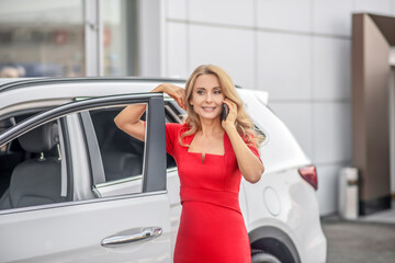 Woman talking on smartphone near car