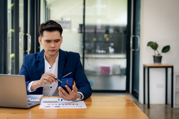 young businessman looking at market research report Analyze statistical data in charts. Develop a growth strategy working on a laptop alone in his office