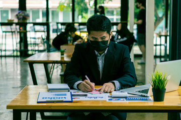 young businessman looking at market research report Analyze statistical data in charts. Develop a growth strategy working on a laptop alone in his office