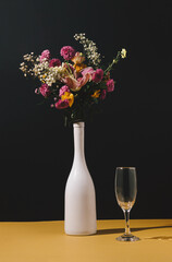Still life of wine bottle with various autumn flowers and glass on the table. Nature concept. Floral Greeting card. Colorful flower background.