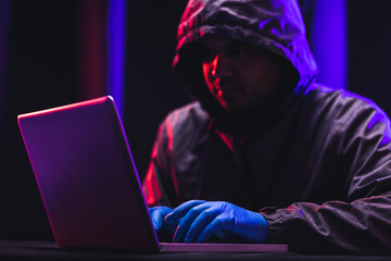 Hackers wear hoods to cover their faces. Hacking to steal important information. Use a computer to release malware viruses Ransom and harass organizations. He sitting in the dark room with neon light
