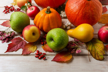 Fall decor with pumpkins, orange squash, red berries and apples