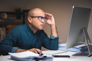 Young asian business freelancer working at late night. He was very busy checking paperwork and had...