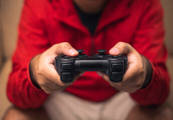 Close up male hands holding joystick game console. Young man playing video game online.