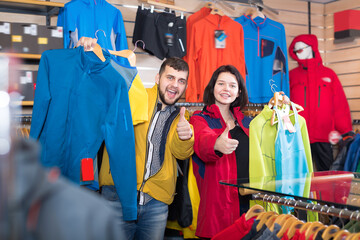 Adult couple boasting various sportswear items in sports clothes store