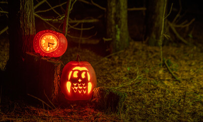 Carved Halloween pumpkins lit by candle light at night one pumpkin carved as an owl and the other...