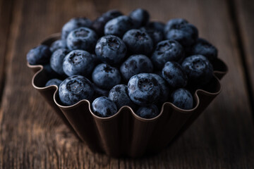 Blueberries in small baking dish ready for making cupcakes on rustic background. Selective focus. Shallow depth of field.