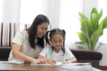 Happy asian little girl with mother teaching homework, Study From Home idea concept