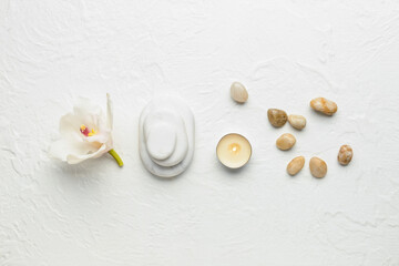 Fototapeta na wymiar Spa stones with flower and burning candle on white background