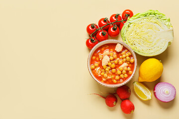 Bowl with homemade pozole soup and vegetables on color background