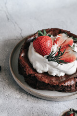 Flourless chocolate cake with whipping cream and strawberry on concrete background. Homemade cake concept.