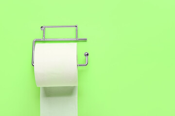 Holder with toilet paper roll on green background