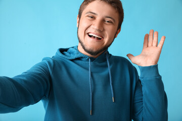 Stylish young man taking selfie on color background