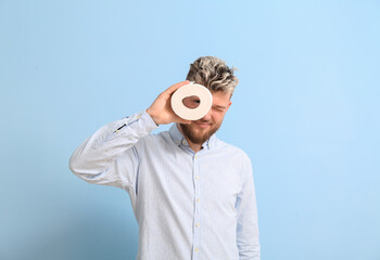 Fototapeta premium Young man with toilet paper on color background