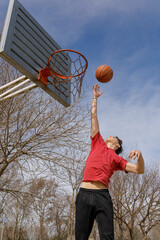 Young athlete training on a basketball court in the outdoor park.