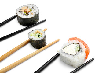Chopsticks with tasty sushi rolls on white background