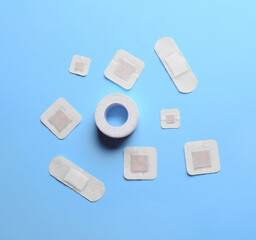 Different elastic medical plasters on blue background