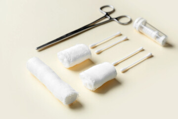 Medical bandage rolls, cotton buds and surgical tool on color background, closeup